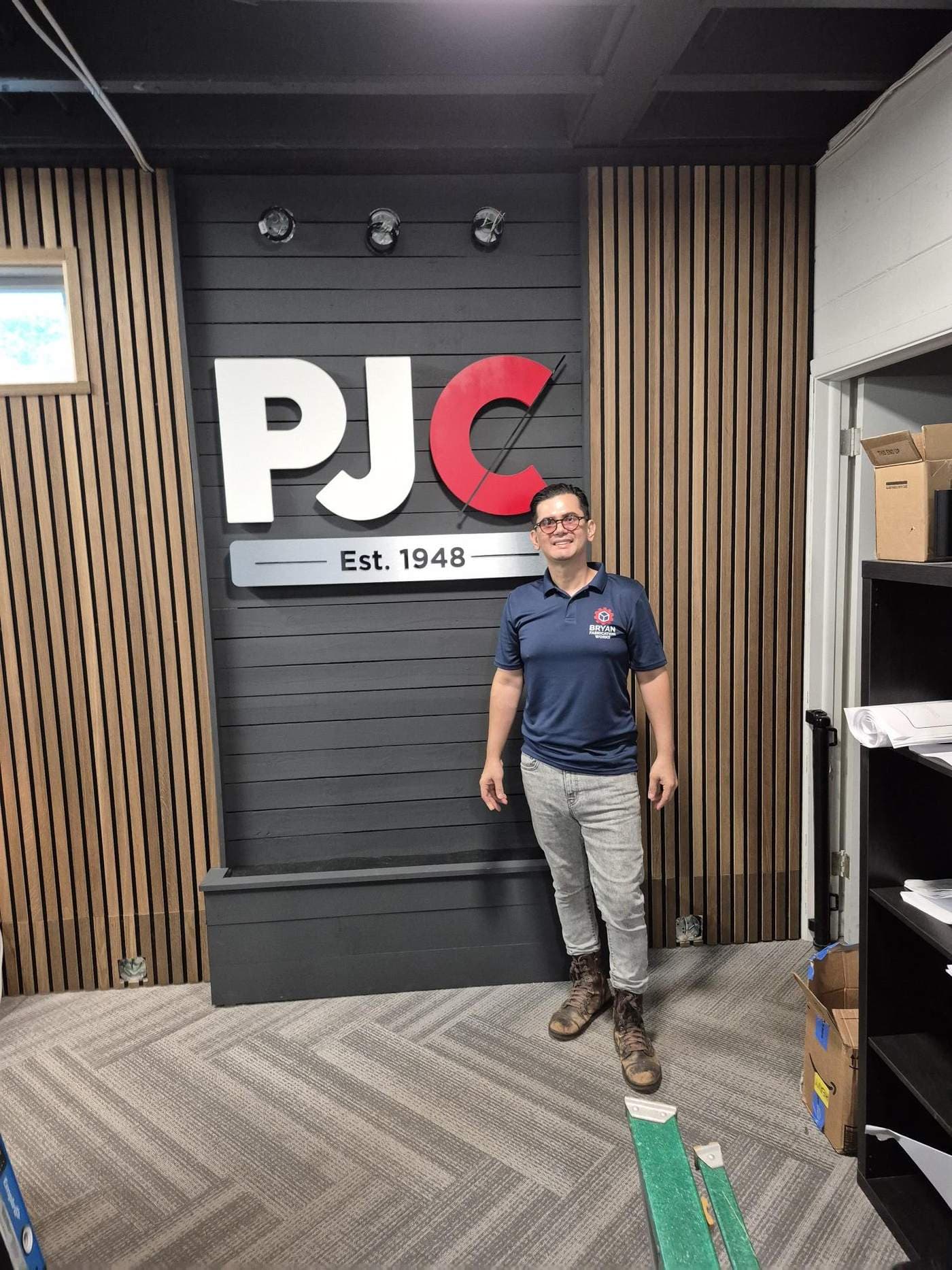 Bryan, owner of Bryan Fabrication Works, beside a dimensional lobby sign his shop built in Tampa