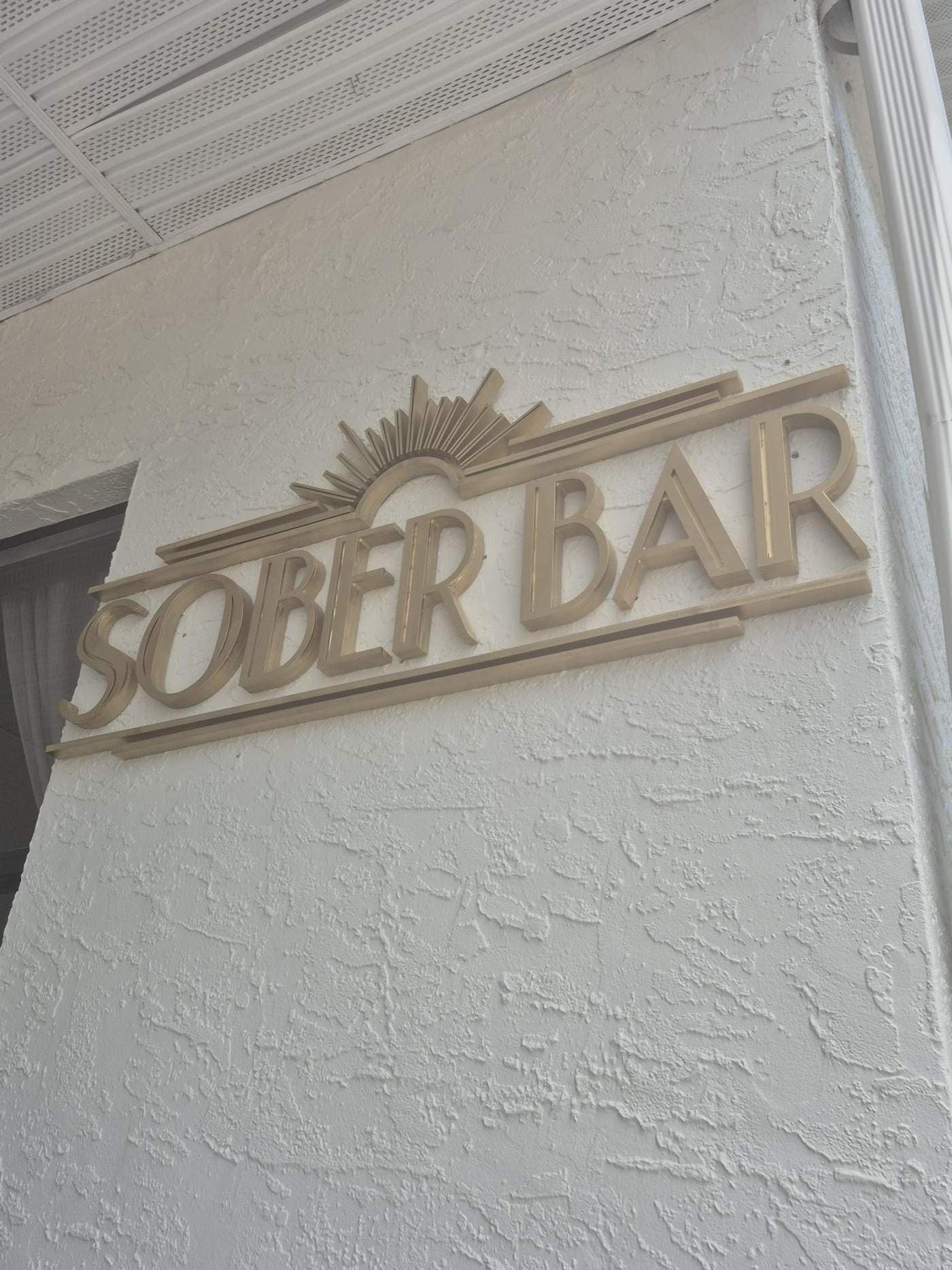 Detail of layered gold art deco lettering and rule lines on a stucco storefront