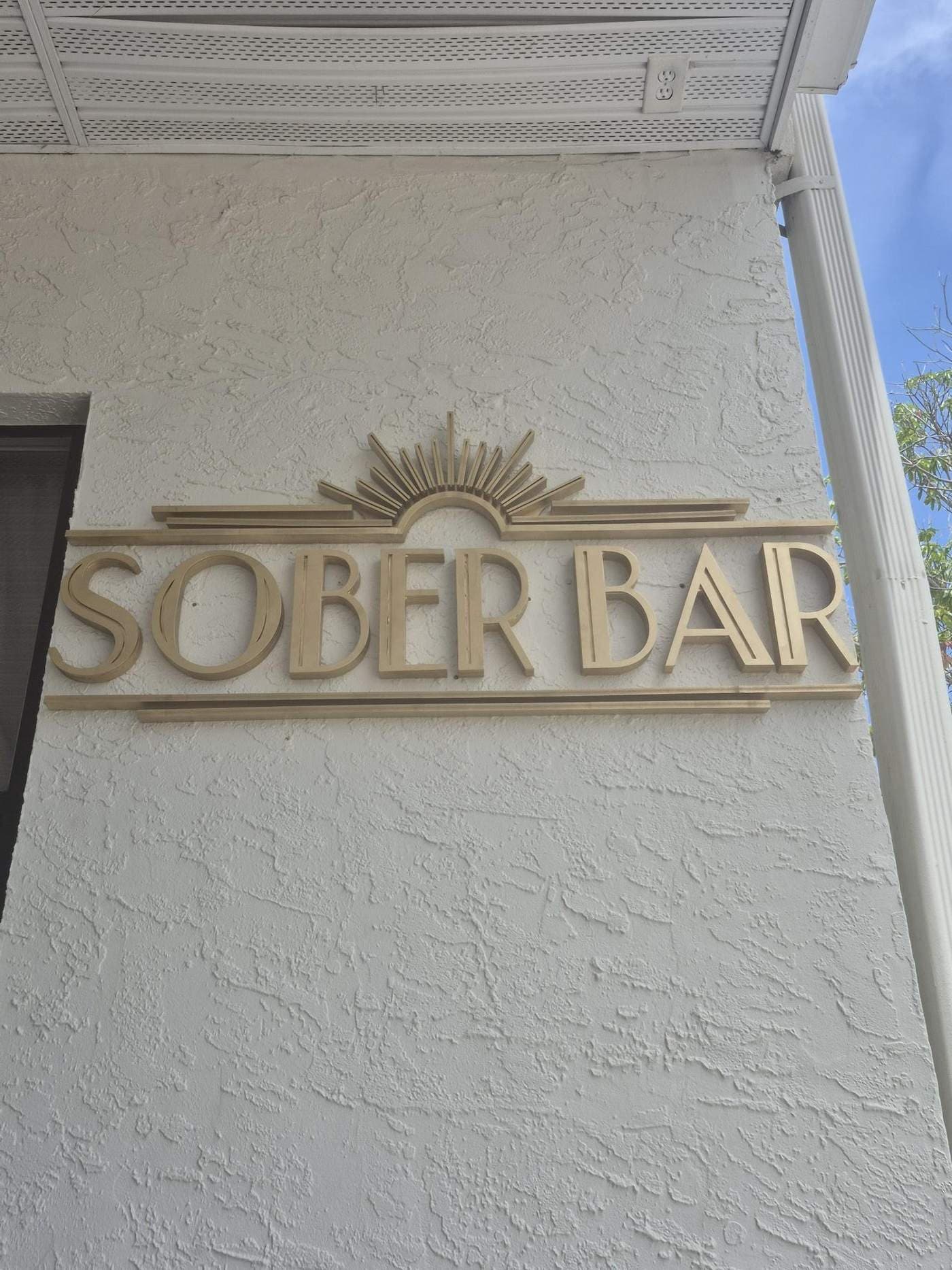 Gold art deco dimensional letters and sunburst mounted on a covered storefront wall