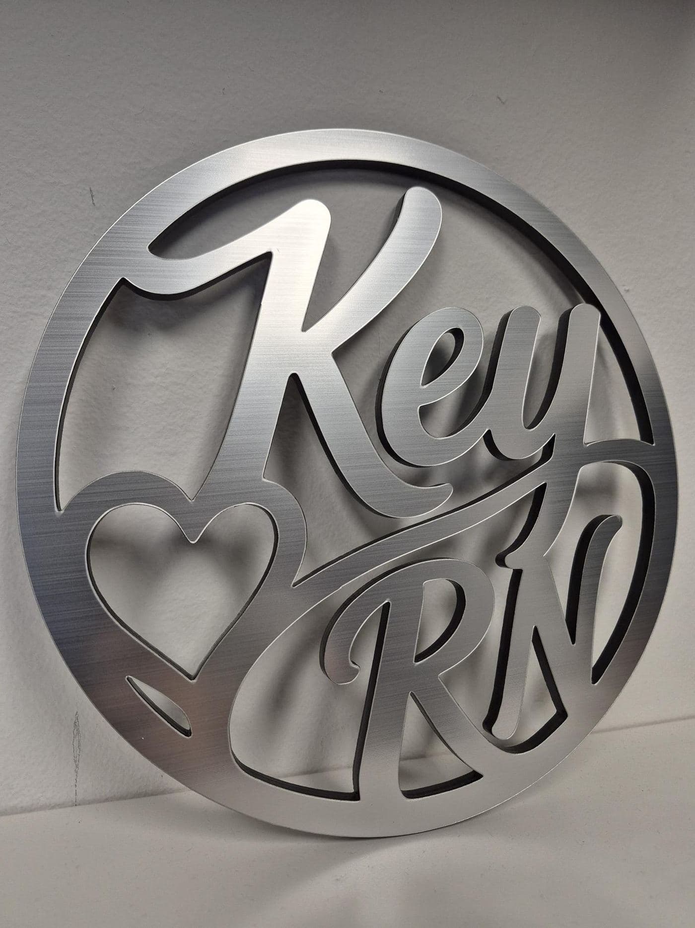Round brushed metal-finish monogram sign with cut-through script lettering