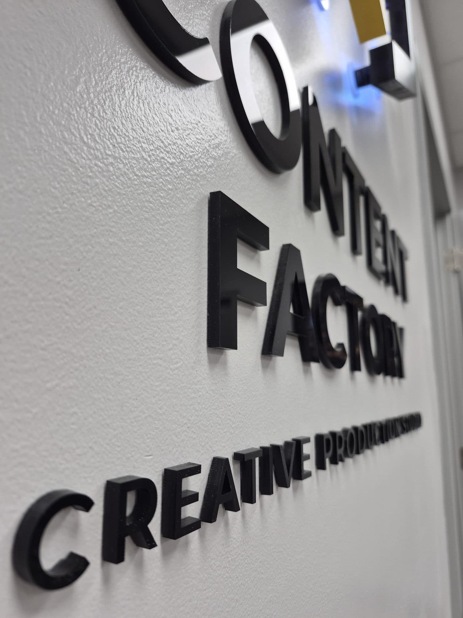 Close-up of gloss black acrylic dimensional letters mounted on a white wall