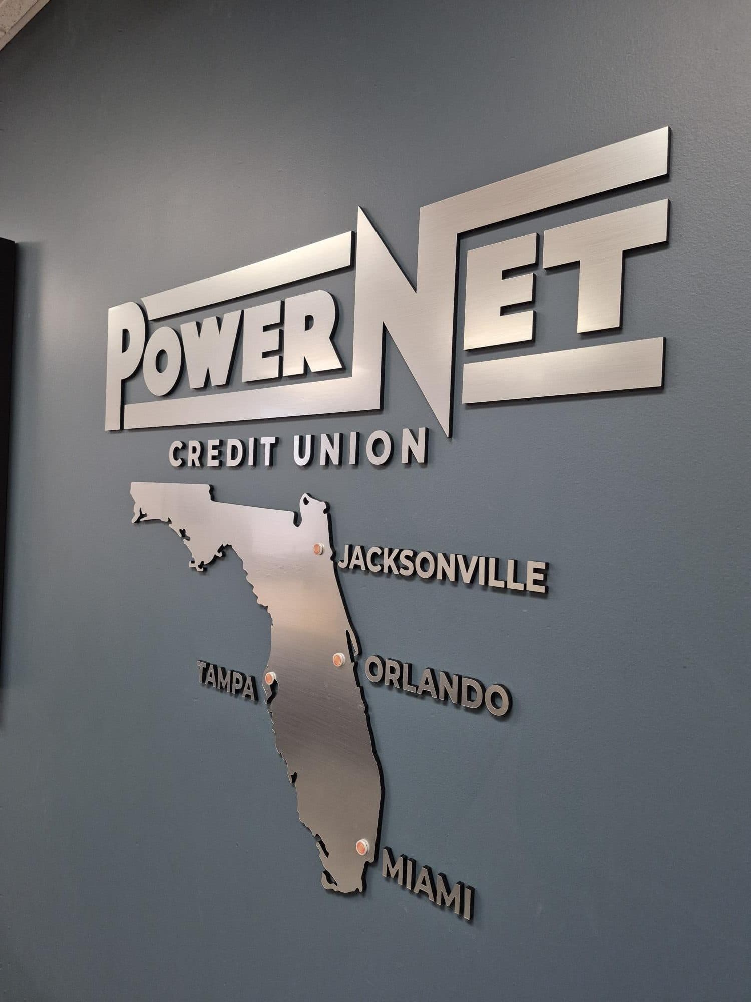 Angled detail of a brushed metal-finish lobby sign showing letter depth and shadow